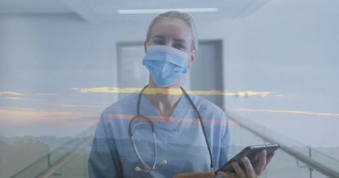 Masked nurse holding tablet and stethoscope with sunset horizon double exposure for telemedicine