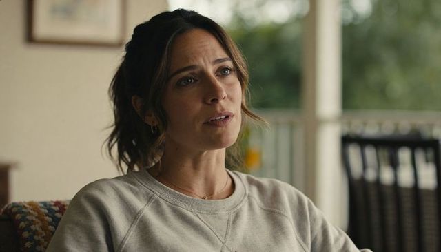 Thoughtful woman listening on porch in gray sweatshirt cozy living room soft light