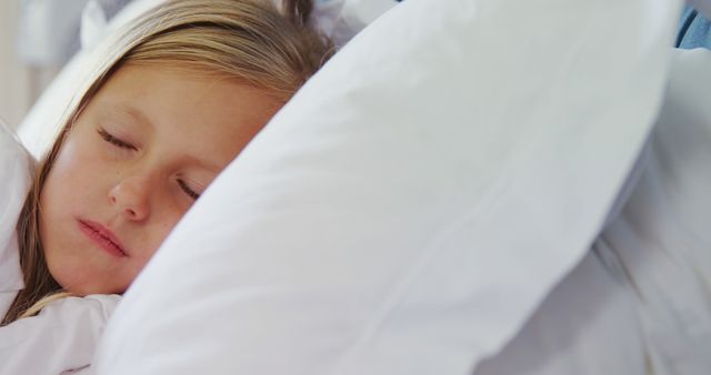 Child sleeping peacefully in bed with white pillows. Ideal for concepts of children's sleep, bedtime routines, relaxation, and comfort. Excellent for use in websites, blogs, and articles focusing on children's health and parenting advice. Perfect for ads promoting bedding, children's sleepwear, and bedtime products.