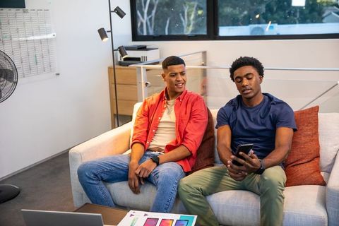 Diverse Colleagues Discussing Designs Using Smartphone and Laptop