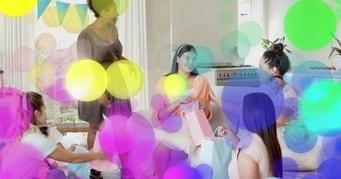 Expectant mother opening gifts at cozy baby shower with friends and colorful bokeh