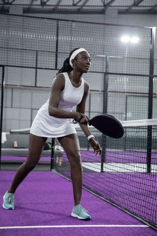 African-american athlete playing paddle on indoor purple court preparing for volley