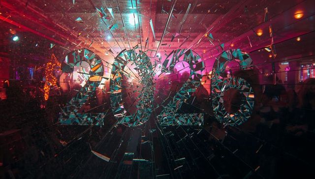 Shattering 2020 mirrored display reflecting nightclub silhouettes in magenta-teal neon vibe