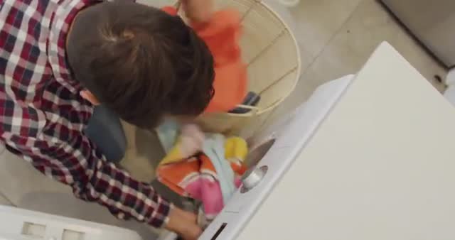 Caucasian man sorting colorful clothes in laundry basket for washing machine. Emphasizes household chores and daily cleaning routine. Ideal for content on home maintenance, laundry tips, or men's involvement in household tasks.