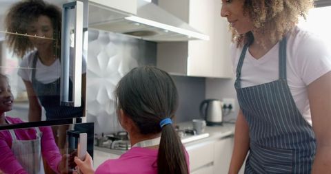 Biracial Mother Baking with Daughter in Modern Kitchen