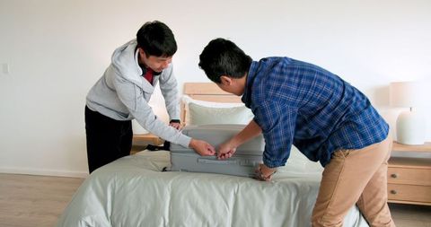 Young Men Packing Suitcase in Bedroom for Travel Adventure