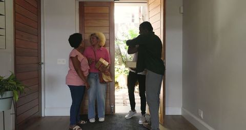 Friends Reuniting With Cheerful Warmth and Gifts by the Front Door