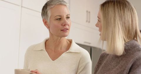 Mother and daughter talking over coffee in cozy modern kitchen