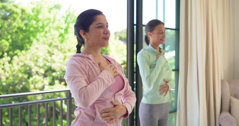 Women practicing deep breathing on sunny balcony for mindfulness and home wellness