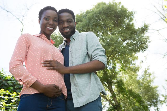 This image is perfect for use in family-oriented advertisements, parenting blogs, maternity and pregnancy articles, and social media posts celebrating family and love. It captures the joy and anticipation of expecting parents in a natural, outdoor setting.