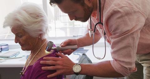 Doctor Examining Senior Woman in Retirement Home During Pandemic