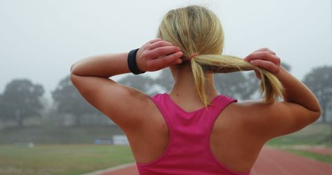 Female athlete preparing for track workout on misty day