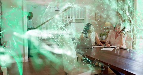 Women collaborating and working from home at dining table with laptop, writing notes