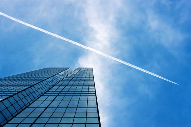 Contrail Over Skyscraper With Reflection on Glass Windows - Download Free Stock Images Pikwizard.com