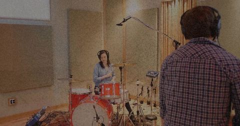 Female musician drumming in soundproof recording studio