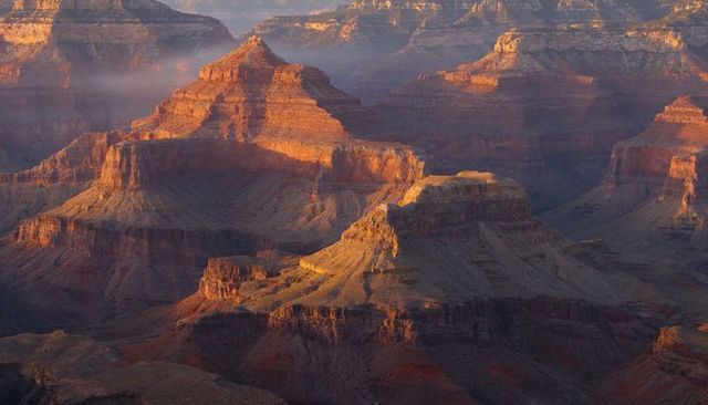 Golden sunrise lighting canyon mesa and butte revealing layered red rock strata