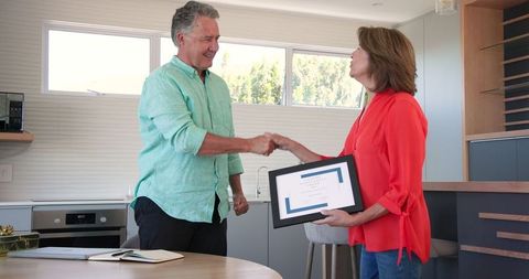 Smiling Senior Couple Exchanging Gift in Modern Kitchen