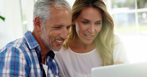 Smiling Mature Couple Engaging with Laptop at Home Interior