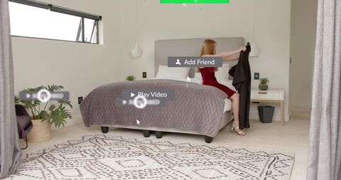 Woman sitting on bed wearing red dress holding coat with streaming overlay minimal bedroom