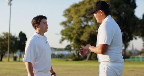 Cricket teammates discussing strategy on sunlit outfield during casual practice session