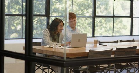 Diverse Colleagues Collaborating at Office Table with Laptop