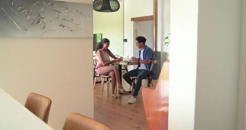 Young african couple enjoying coffee at home dining table during casual conversation