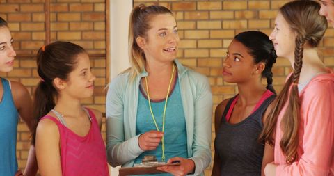 Female coach guides high school girls in basketball training