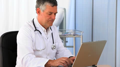 Senior Doctor Focused on Computer with Calm Expertise