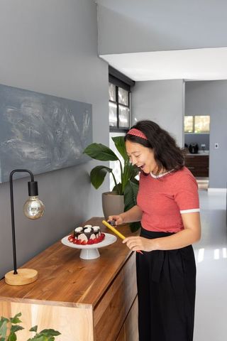 Joyful Woman Preparing Cake in Modern Kitchen Nook