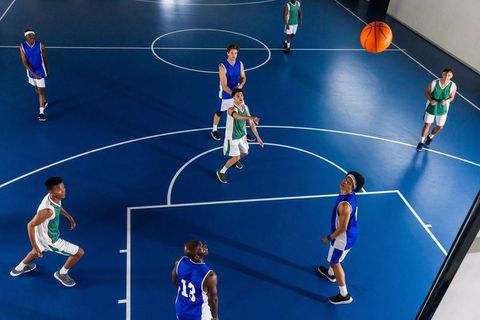 Teenage Basketball Players Competing on Blue Indoor Court