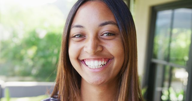 Portrait of happy biracial teenager girl looking at camera and smiling. Spending quality time, lifestyle and adolescence concept.