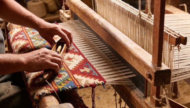 Artisan weaving handwoven rug on traditional wooden loom highlighting colorful geometric pattern