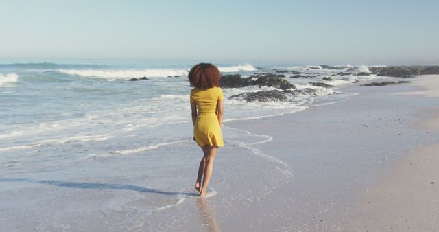 Woman Walking on Beach in Yellow Dress by Ocean Waves - Download Free Stock Images Pikwizard.com