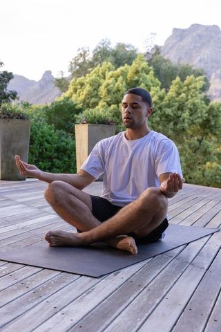 Man Meditating on Wooden Deck Surrounded by Nature