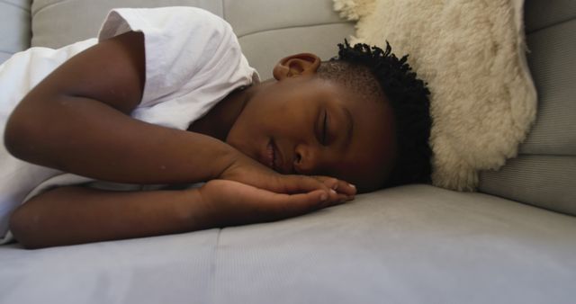 A child sleeping peacefully on a sofa, resting on a soft pillow. Ideal for illustrating themes of childhood, rest, relaxation, home life, and comfort in family or lifestyle contexts.