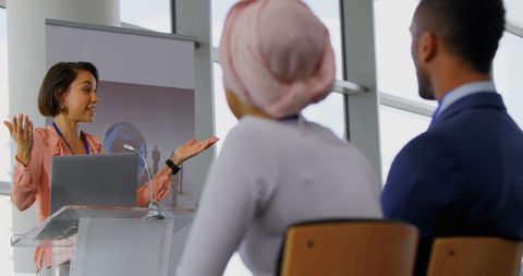 Businesswoman Presents at Seminar with Diverse Audience in Modern Conference Room