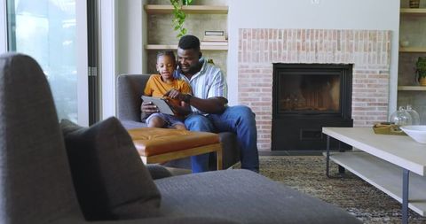 Father and Son Enjoying Time Together on Tablet in Cozy Living Room