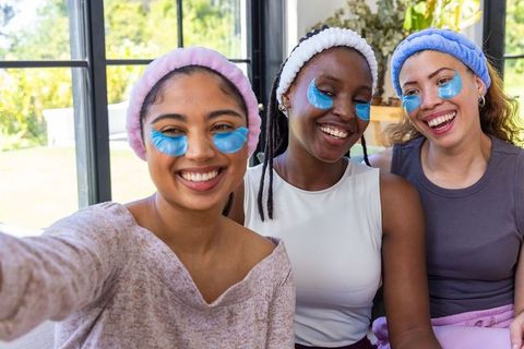 Smiling african american and multicultural friends posing for selfie during at-home spa night