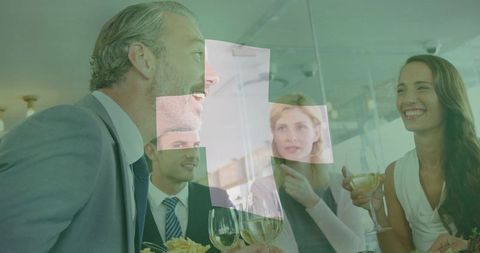 Senior executive speaking during corporate networking dinner with smiling colleagues over drinks