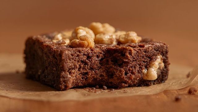 Chocolate brownie square showing moist interior with walnut topping and rustic crumbs