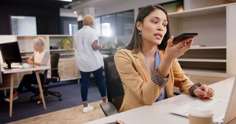 Woman Engages in Conversation on Smartphone at Modern Office Desk