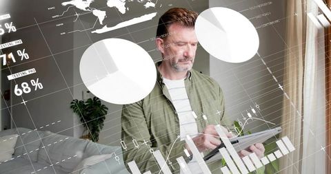 Mature man holding tablet analyzing financial charts with world map overlay at home