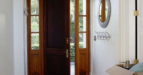 New home owners carrying cardboard boxes into modern house entrance