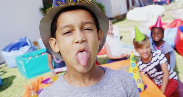 A young biracial boy sticks out his tongue playfully at a birthday party, with copy space - Download Free Stock Photos Pikwizard.com