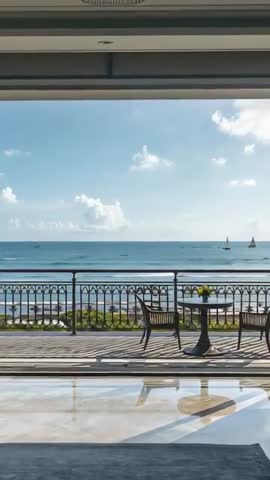 Vertical panning of sunlit seaside terrace showing bistro table, chairs and sailboats