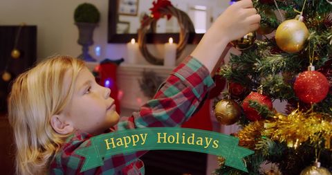 Cheerful Boy Decorating Christmas Tree with Happy Holidays Banner - Download Free Stock Images Pikwizard.com