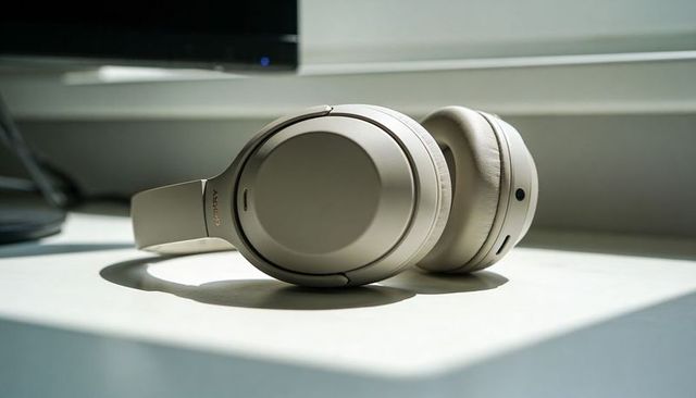 Beige over-ear headphones resting on sunlit desk near monitor for home office audio