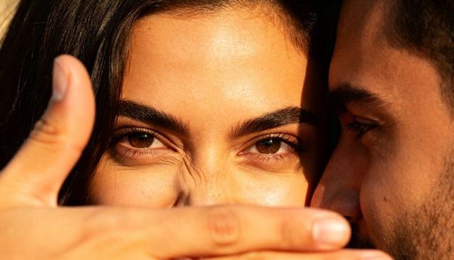 Couple sharing intimate close-up during golden hour, sunlit eyes and hand framing face