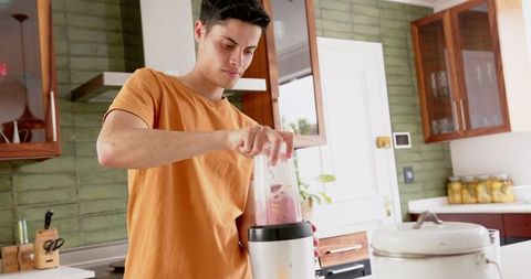 Focused Young Man Making a Healthy Fruit Smoothie in Modern Kitchen