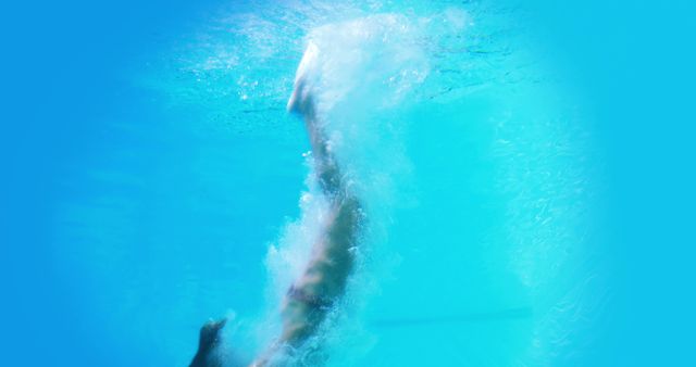 Pretty brunette diving underwater into pool on her holidays
